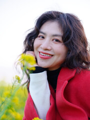A Chinese woman dressed in red stands in a field of rape flowers