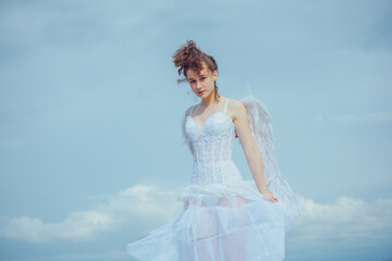 Fototapeta na wymiar Valentines Day. Love and romance. Teenager angel girl with wings, copy space on sky.