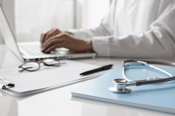 Doctor medical professional working on laptop, focus on stethoscope. Physician, therapist or practitioner filling medical documents, writing prescription for patient. Health care, medicine concept