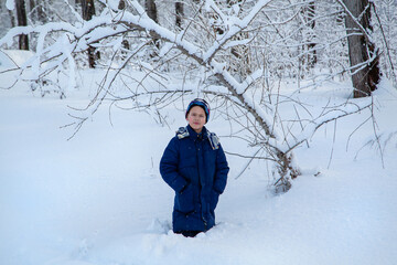 full-length portrait of a boy standing in a winter forest