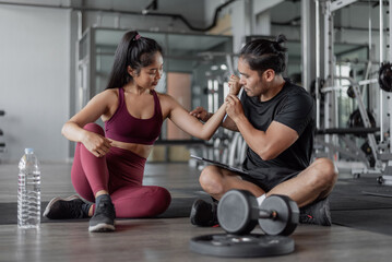 Fototapeta na wymiar Asian woman exercise with personal trainer in gym. healthy woman talking with personal trainer in fitness.