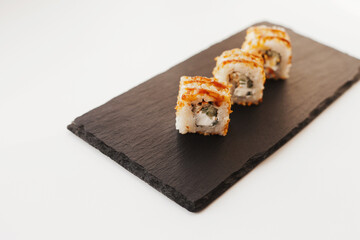 Sushi japan food on black plate at sushi restaurant or takeout with chopsticks on white. Delicious sushi japanese food with chopsticks fresh at the restaurant or takeout delivery.