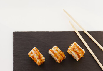 Sushi japan food on black plate at sushi restaurant or takeout with chopsticks on white. Delicious sushi japanese food with chopsticks fresh at the restaurant or takeout delivery.