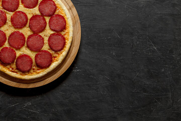 Pepperoni pizza Italian cooked whole uncut, top view dark background, with space to copy text.