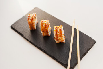 Sushi japan food on black plate at sushi restaurant or takeout with chopsticks on white. Delicious sushi japanese food with chopsticks fresh at the restaurant or takeout delivery.
