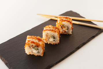 Sushi japan food on black plate at sushi restaurant or takeout with chopsticks on white. Delicious sushi japanese food with chopsticks fresh at the restaurant or takeout delivery.