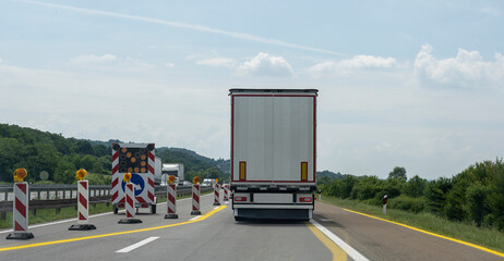 White Semi-trailer driving along highway. Goods Delivery by roads. Services and Transport logistics. Crowded on the highway. Highway works.