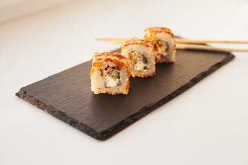 Sushi japan food on black plate at sushi restaurant or takeout with chopsticks on white. Delicious sushi japanese food with chopsticks fresh at the restaurant or takeout delivery.