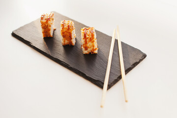 Sushi japan food on black plate at sushi restaurant or takeout with chopsticks on white. Delicious sushi japanese food with chopsticks fresh at the restaurant or takeout delivery.