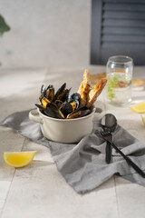 Cooked, boiled mussels with lemon juice, parsley and toasted bread in white bowl (plate) on the table. Seafood, copy space. 