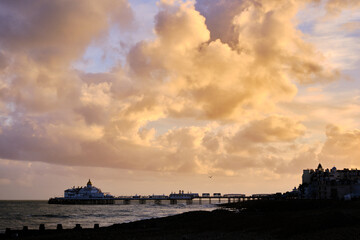 Golden cumulous clouds above Eastbourne Pier. High contrast. East Sussex England UK