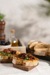 Ciabatta bread sandwich with humus and dried tomatoes, arugula leaves on white table. Italian traditional food - bruschetta, antipasto. with ingredients. Copy space. 