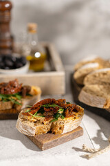 Ciabatta bread sandwich with humus and dried tomatoes, arugula leaves on white table. Italian traditional food - bruschetta, antipasto. with ingredients. Copy space. 