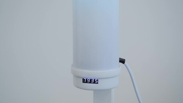 Antibacterial radiator in the room. Disinfection of air in the office or at home. Man's hand turn off ultraviolet antibacterial bactericidal quartz medicine lamp.