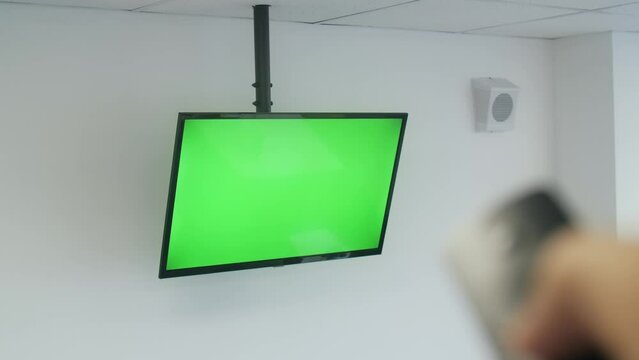 Male hand operating a TV remote control on a TV with chroma key.