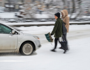 Dangerous situation on city road on zebra crossing in winter time. Intentional motion blur