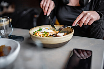 woman hand eating donburi with chicken and rice using knife and fork fom bowl