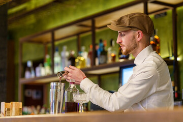 Male barkeeper pouring alcohol into shaker