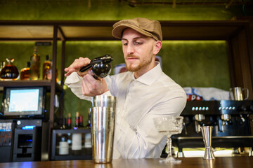 Male barkeeper squeezing lemon into cocktail in a pub