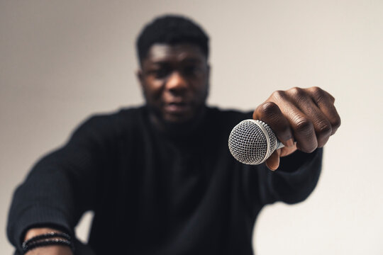 person of color holding exhibiting microphone studio - close up shot. High-quality photo