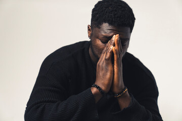 anxious praying black man with hands in his face white background - close-up shot. High-quality photo