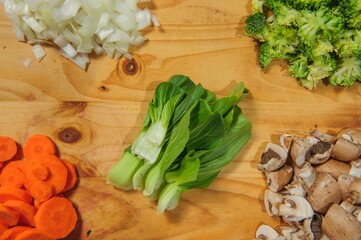 Creative vegetarian cooking at home concept with fresh healthy vegetables chopped, salads and kitchen wooden utensils, top view with copy space