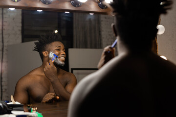 adult african man shaving indoors at the mirror 