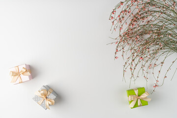 Flat lay, top view, white background, small gift boxes and a bush of dried flowers with pink cute...