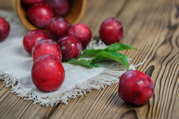 Large ripe plums spilled out of an overturned wicker basket onto a napkin on the table