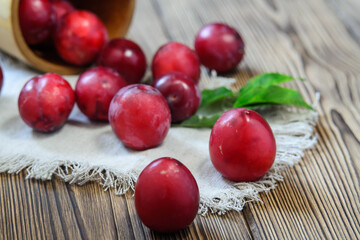 Large ripe plums spilled out of an overturned wicker basket onto a napkin on the table