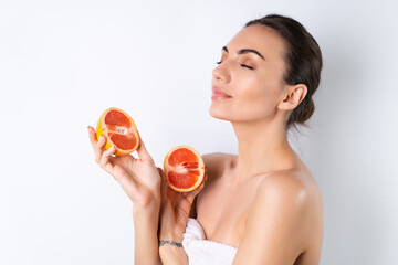 Close-up portrait of topless woman with perfect skin and natural make-up, full nude lips, holding fresh citrus vitamin C grapefruit.