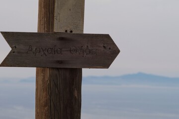 A wooden greek sign showing the path to the ancient village of Fira in Santorini Greece