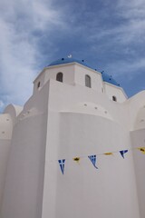 View of a whitewashed orthodox church with byzantine and greek flags in Santorini Greece 