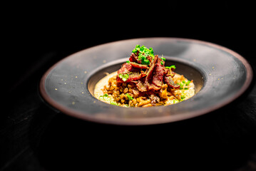 Spelt with venison jerked beef in black plate
