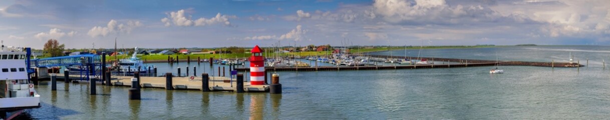 View of the coastal landscape with port entranse and marina at Wyk auf Föhr from a ferry. Red pier light in harbour of Wyk auf Föhr. North Sea island in North Frisia, Schleswig-Holstein.
 - obrazy, fototapety, plakaty