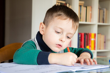 6 years old caucasian boy learning at home mathematics. Elementary age.