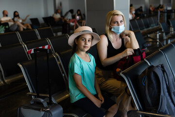 Fototapeta premium happy young mother with daughter at airport while waiting for their flight