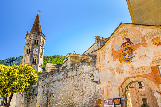Finalborgo, Finale Ligure, Italy. May 5, 2021. Detail of the external facade of Porta Reale with the bell tower of the Church of San Biagio on the left.