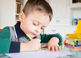 6 years old caucasian boy learning at home mathematics. Elementary age.