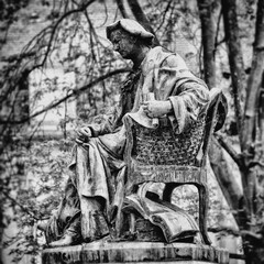 statue d'un personnage dans un jardin public, assis dans un fauteuil