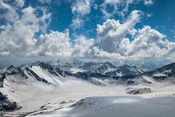 Fototapeta premium Mountain clouds over beautiful snow-capped peaks of mountains and glaciers. View at the snowy mountains.