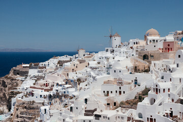 Fototapeta na wymiar View of Oia town with mills in Santorini island in Greece. Summer vacation and holiday concept, luxury travel. Wonderful scenery, cruise ships and white architecture. Amazing landscape.