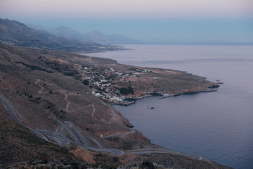 Amazing winding backroads of the wild southern coast of the island of Crete, Greece, with view on sea and blue sunset sky. Wonderful landscapes, mountain and the sea on the coastline. Copy space