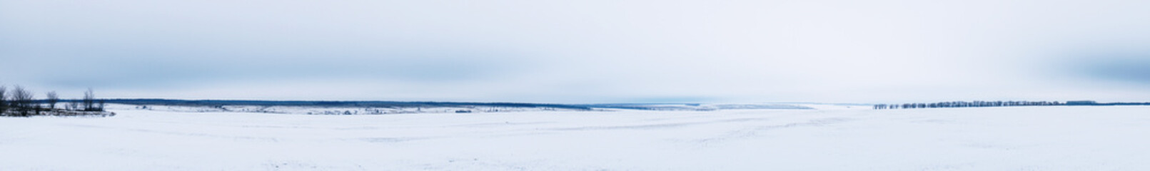 Fototapeta na wymiar Panorama Winter view of a snow-covered plain or steppe in cloudy weather
