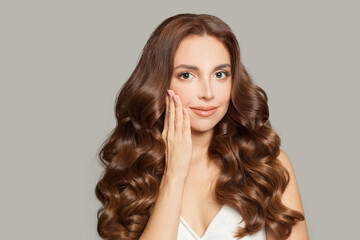 Naklejka premium Attractive female model with long shiny brown wavy hair . Beautiful woman with curly hairstyle .