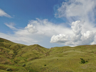 Obraz na płótnie Canvas Peaceful landscape green hills under cloudy blue sky