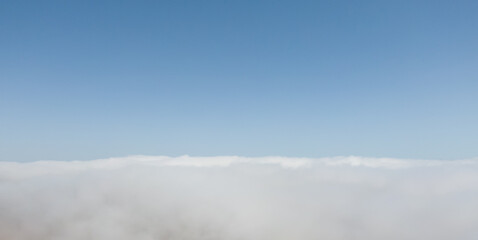 Aerial view of dense fog lying on the ground under a clear blue sky
