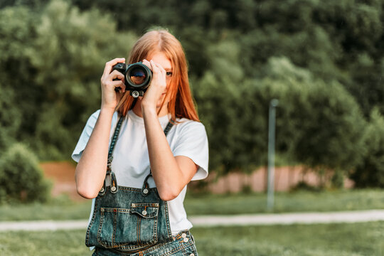 Ginger teen, girl taking photos with camera. Copy space