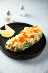 Healthy avocado toast with scrambled eggs and caviar