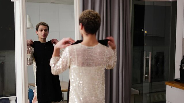 A man trying his new black dress in front the mirror at home